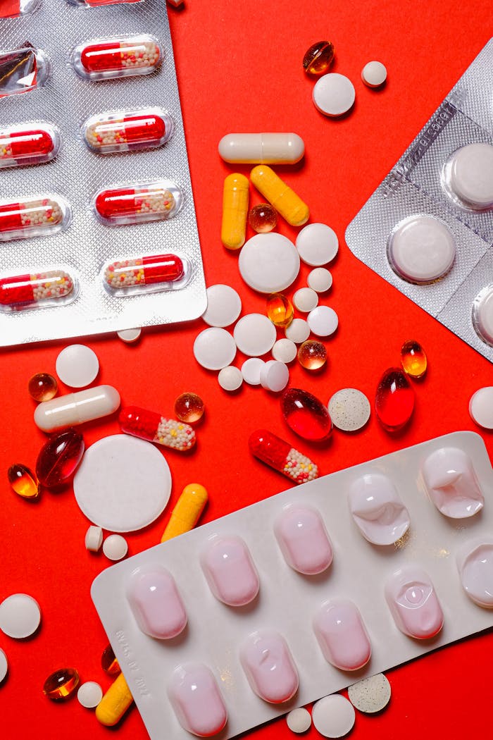 Colorful assortment of pills and tablets spread across a vibrant orange background.