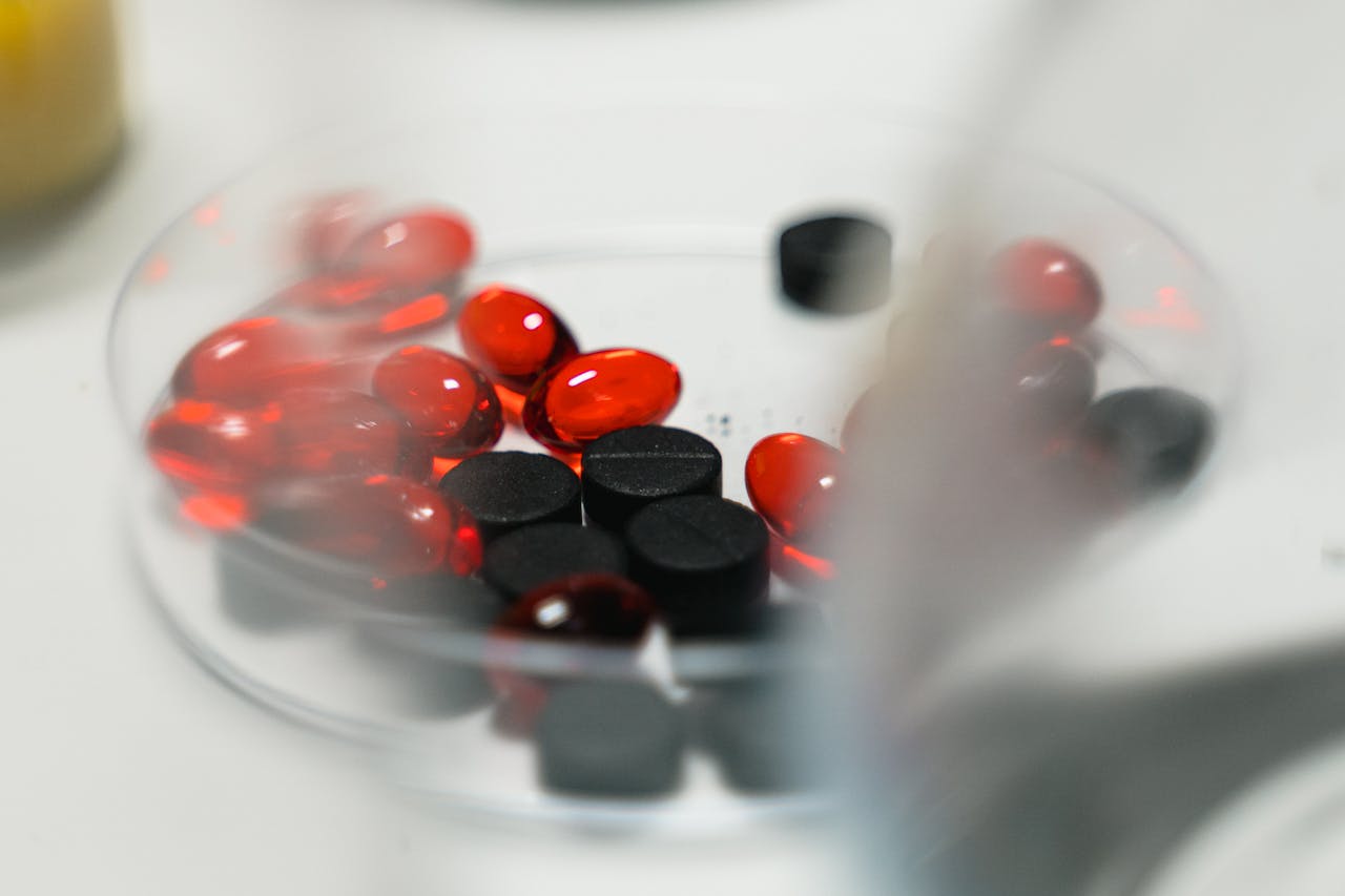 Red and black pills in a petri dish, ideal for healthcare and pharmaceutical themes.